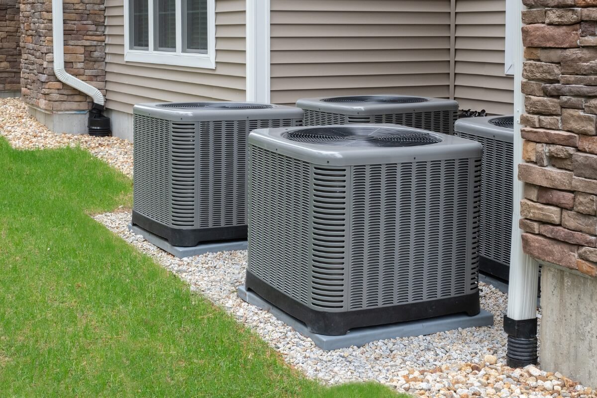 three air conditioners in front of a house