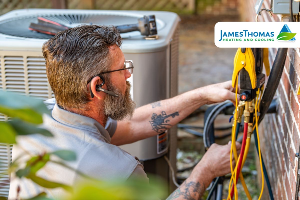 A bearded man wearing glasses repairs an air conditioner, focusing on HVAC maintenance.
