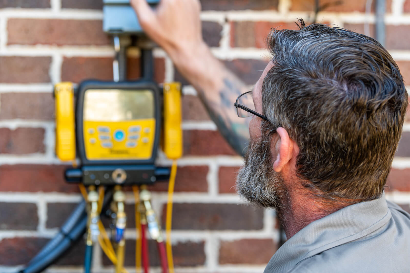 A man measures the temperature with a meter while fixing an air conditioning unit.