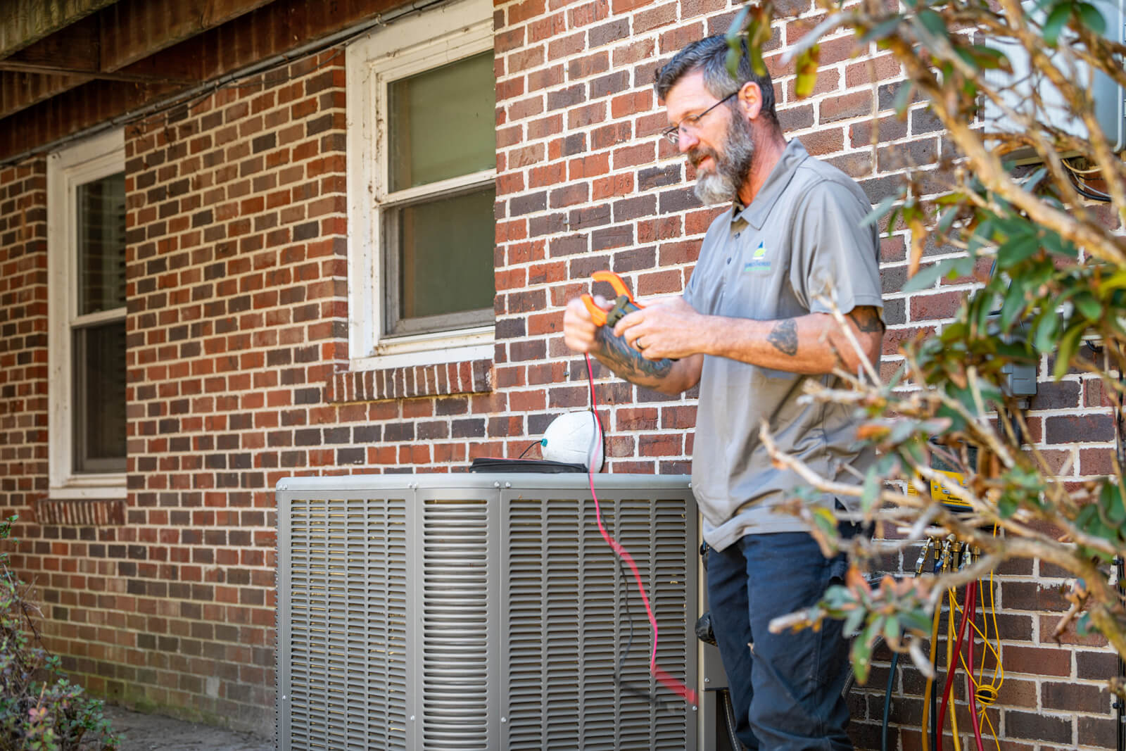 A man repairs an air conditioner, focusing on the HVAC system components.