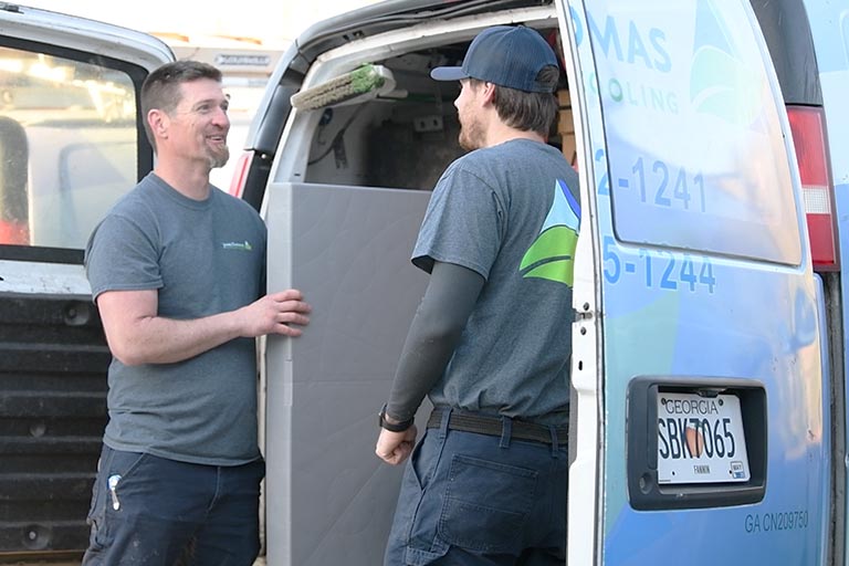 Heating-&-Cooling-Services-in-Morganton Two technicians in matching shirts interact as they load equipment from a service van, with tools and supplies visible inside.