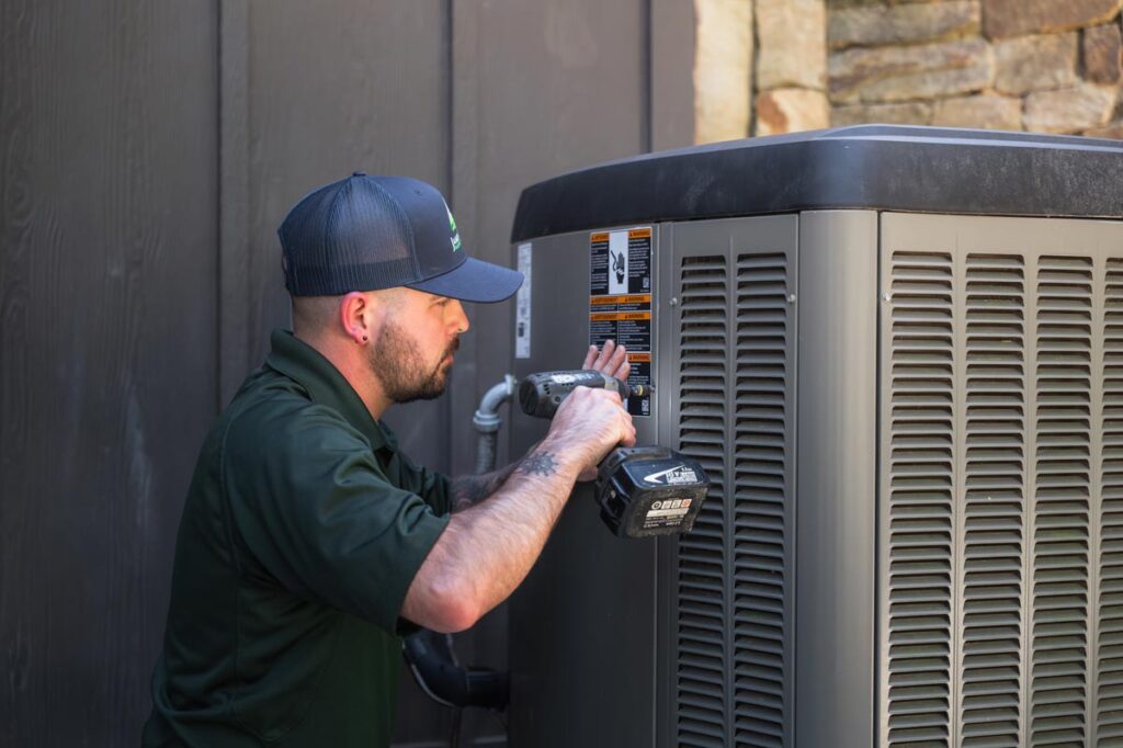 HVAC technician working on an outdoor air conditioning or heat pump unit at a residential property.