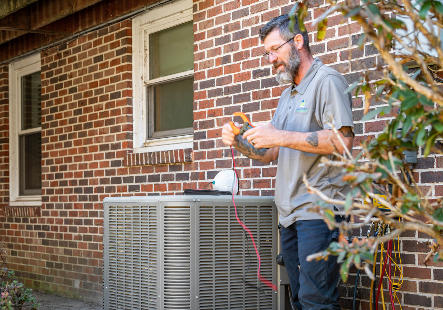 A man repairs an air conditioner, focusing on the HVAC system components.